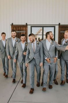 a group of men standing next to each other in front of a white barn door