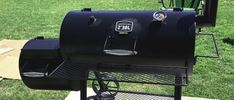 a large black bbq grill sitting on top of a grass covered field