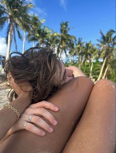 a woman laying in the sand with her arm around her body and wearing a diamond ring