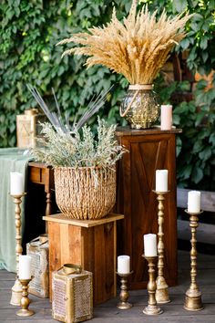 a table with candles, vases and plants on it