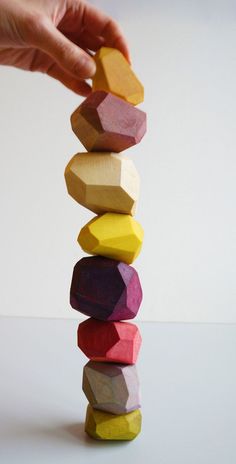 a stack of colored wooden blocks being held by a person's hand over the top