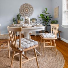 a dining room table with two chairs and a round rug on the floor in front of it