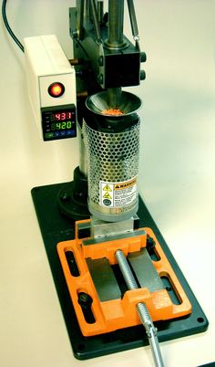 a machine that is sitting on top of a black tray with an orange tool in front of it