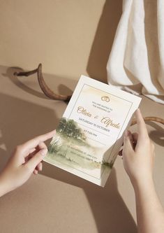 a person holding up a wedding card in front of an antler's head