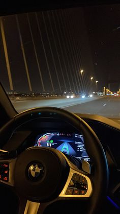 the interior of a car driving on a highway at night with lights in the background