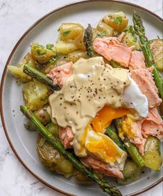 a white plate topped with asparagus, potatoes and an poached egg