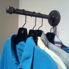 three shirts hanging on a rack in front of a wall with a coat hanger