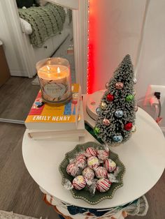 a table topped with lots of candy next to a lit candle and a christmas tree