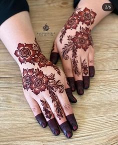 two hands with henna tattoos on them sitting on a wooden table next to each other