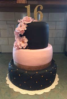 a black and pink cake with flowers on top