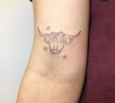 a woman's arm with a cow head tattoo on the left side of her arm