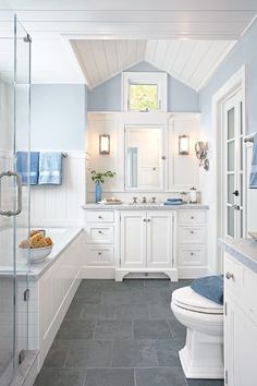 a white bathroom with blue accents and tile flooring, along with a walk in shower