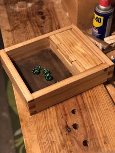 a wooden box with green dices in it on a table next to other woodworking tools