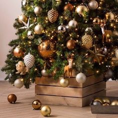 a small christmas tree with gold and silver ornaments on the top is in a wooden box