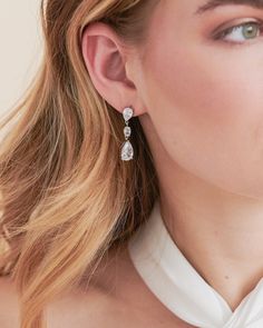 Timeless & chic, you'll never want to take off our Miley CZ Earrings. Crafted with two pear-cut CZs connected by an oval CZ center, these dangle earrings are lightweight for easy all day wear. Cubic zirconia Measures 0.5" x 1.25" long Hypoallergenic, lead-free & nickel-free Style #4383 Wedding Day Earrings, Dainty Dangle Earrings, Wedding Wardrobe, Timeless Chic, Floral Studs, Crystal Dangle Earrings, Popular Jewelry, Sparkle Earrings, Chain Extenders