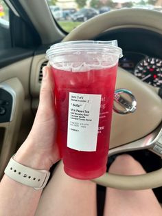 a person holding a drink in their hand while sitting in the driver's seat