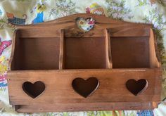 a wooden shelf with three heart shaped holes on it's sides and two hearts hanging from the top