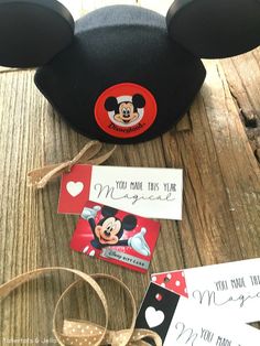 a mickey mouse hat and some tags on a wooden table with other items around it