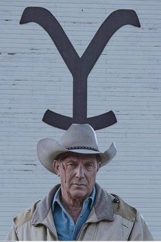 an older man wearing a cowboy hat standing in front of a building with the y on it