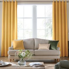 a living room filled with furniture and yellow curtains