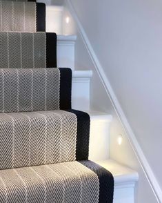 the carpeted stairs are lined with black and white herringbone rugs on each side