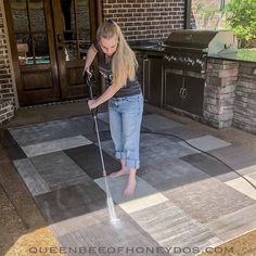 a woman is using a sprayer to clean the floor in front of her house