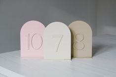 three small white and pink house numbers sitting on top of a table next to each other