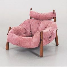 a pink chair sitting on top of a white floor next to a wooden leg rest