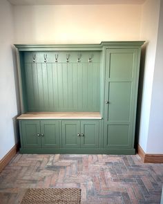 an empty room with green cabinets and drawers on the wall, in front of a rug