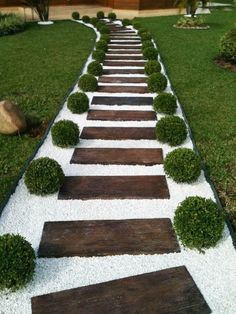 a garden path made out of wood and white gravel with grass growing on the sides