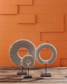 two sculptures on stands in front of an orange wall