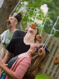 people eating donuts hanging from strings in the air