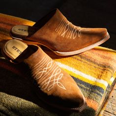 The Reed Western Mules have a brown suede upper and feature a snip toe with unique toe bug embroidery. Additional details include a stacked heel, cushioned leather insoles, premium brass nails and hand-driven lemonwood pegs that enable the boot to withstand the elements by expanding and contracting with any moisture the boot may encounter. Our western boots are handcrafted with the same care and consideration that goes into our legendary headwear, resulting in the ultimate mix of heel-to-toe com Western Leather Mules With Pointed Toe, Western Style Leather Mules With Pointed Toe, Western Style Slip-on Mules With Leather Sole, Western Closed Toe Mules For Fall, Western Leather Mules For Fall, Western Style Closed Toe Mules For Fall, Suede Snip Toe Boots With Stitched Sole, Suede Boots With Snip Toe And Stitched Sole, Bug Embroidery