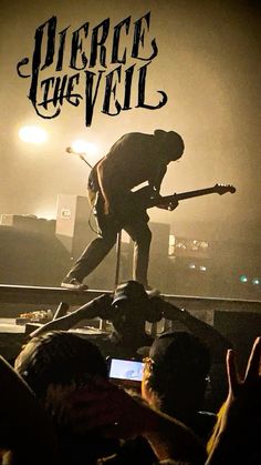 a man standing on top of a stage holding a guitar in front of his face