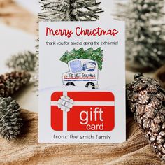 a christmas card sitting on top of a wooden table next to pine cones and fir trees