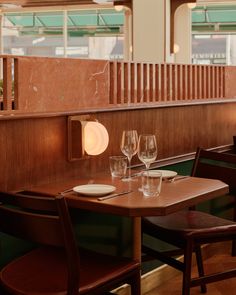 two empty wine glasses sit on a table in the middle of a room with wood paneling