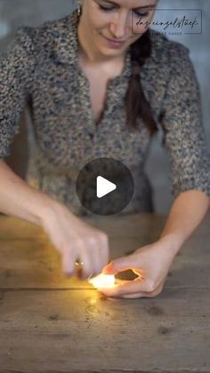 a woman lighting a candle on a wooden table