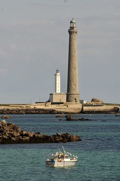 a small boat in the water near a light house