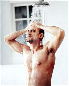 a man standing under a shower head with his hands on his head and water pouring from the faucet