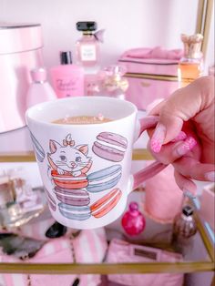 a person holding a coffee cup in front of a shelf with pink items on it