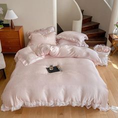 a bed with pink comforters and pillows in a room next to a stair case