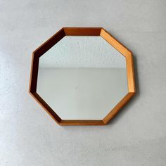 a mirror on the wall that is shaped like a hexagonal object with a wooden frame