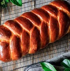 a loaf of bread sitting on top of a cooling rack next to some green leaves