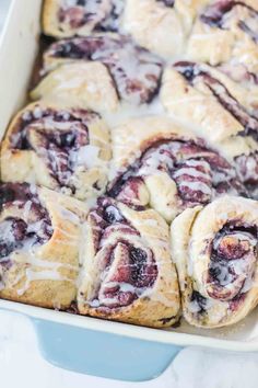 blueberry rolls in a baking dish with icing drizzled on top