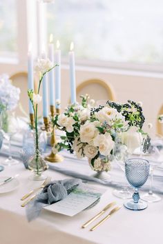 the table is set with white flowers and candles