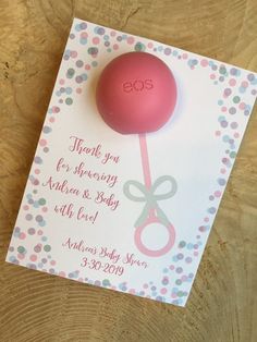 a thank you card with a pink ball and scissors on it, sitting on a wooden table