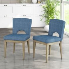 two blue chairs sitting next to each other in a room