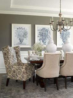 a dining room table with chairs and pictures on the wall behind it in front of a chandelier