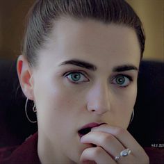 a close up of a person with a ring on her finger and an earring