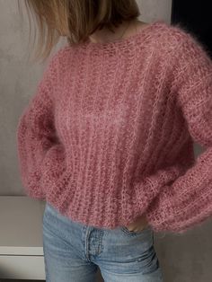 a woman is wearing a pink sweater and jeans